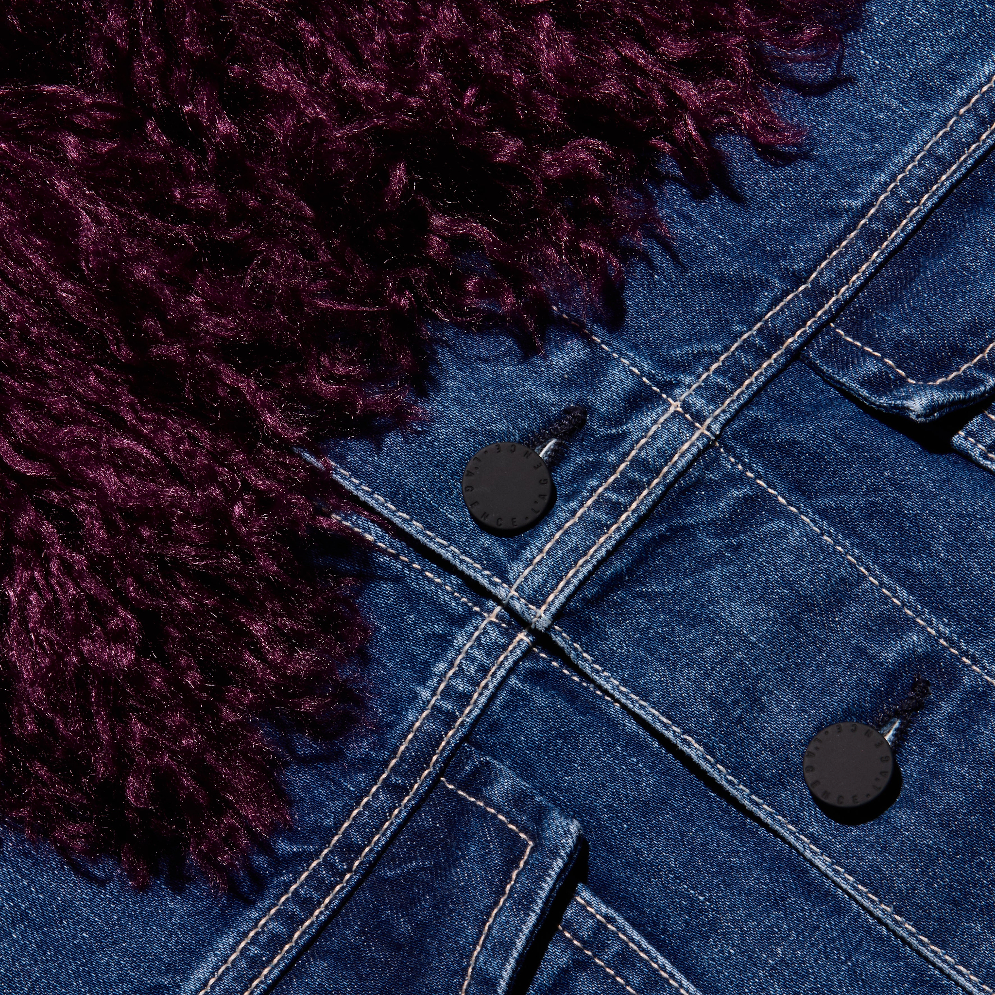 Close-up of a Bronson Jean Jacket, featuring a cropped blue denim design with a dark purple faux-fur collar and black buttons.