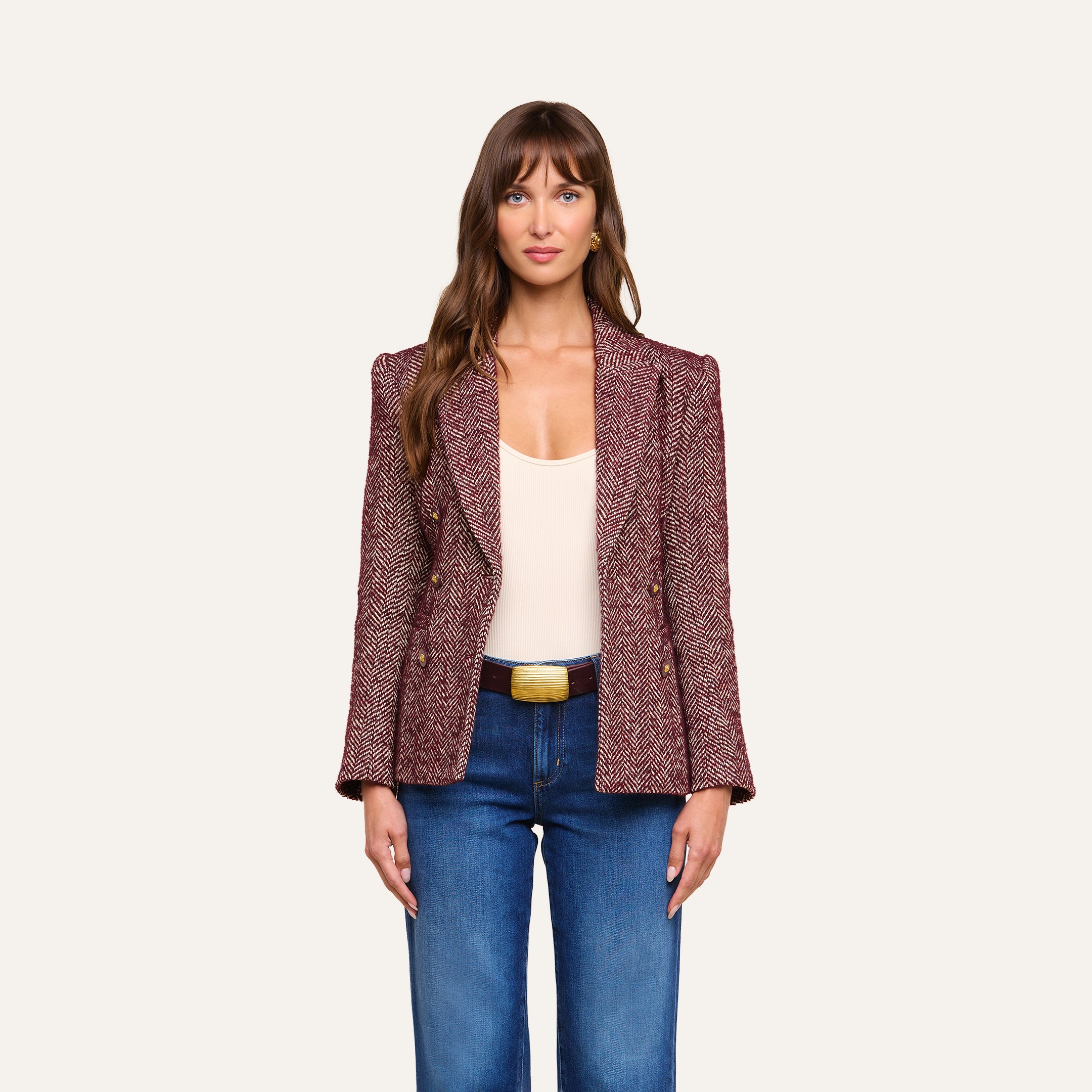 A woman wearing the Karima Tweed Blazer in red, paired with a white top and blue jeans, stands facing forward against a plain light background.