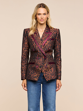 A woman stands facing forward, wearing the Kyomi Double-Breasted Blazer with maroon trim and blue jeans, in front of a beige background.