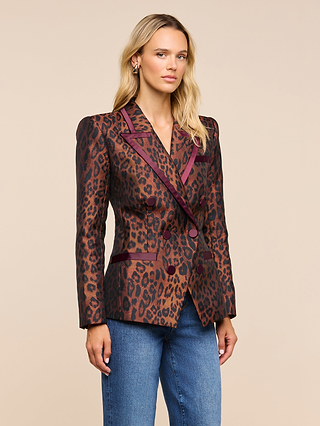 A woman wearing the Kyomi Double-Breasted Blazer with brown leopard jacquard, satin trim, and blue jeans stands against a beige background, looking at the camera with a neutral expression.