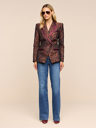 Woman in sunglasses wearing the Kyomi Double-Breasted Blazer, blue jeans, and maroon shoes stands against a beige background.