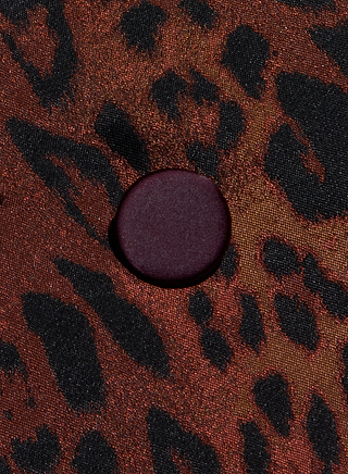 A close-up of a fabric with a red and black leopard print pattern, featuring a single round, dark red button in the center—perfectly capturing the bold detail of the Kyomi Double-Breasted Blazer.