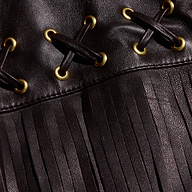 Close-up of the Luci Fringed Leather Jacket, featuring black leather with gold eyelets, black lacing in an X pattern, and a long fringe detail at the bottom.