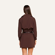 A woman with long brown hair is standing with her back to the camera, wearing the Kade Windbreaker and a matching skirt.