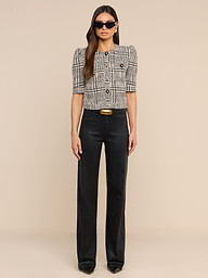 A woman wearing sunglasses and the Allegra Cropped Tweed Jacket layered over a short-sleeve plaid blouse, paired with black high-waisted pants and black shoes, stands against a plain white background, facing forward with a neutral expression.