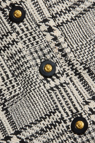 Close-up of the Allegra Cropped Tweed Jacket in a black and white plaid tweed, featuring four round black buttons with textured gold centers.