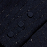 Close-up of the Risa Double-Breasted Blazer sleeve featuring three fabric-covered buttons in a row, highlighting the fine texture and subtle shimmer of Lurex woven into its dark pinstripe material.