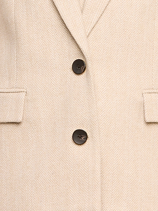 Close-up of the Amelie Blazer in light beige with a herringbone pattern, inspired by New York Fashion Week, featuring dark buttons and two horizontal welt pockets on either side.