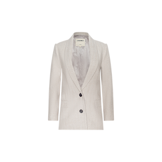 The Amelie Blazer is a women’s fitted blazer in light beige, crafted from soft herringbone tweed. It features a notched lapel, two front buttons, two pockets, and a smooth inner lining. Displayed against a plain white background, this style was seen at New York Fashion Week.