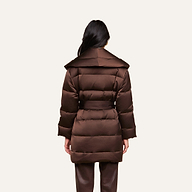 A person with long dark hair, seen from behind, is wearing the Glacier Shawl Puffer Jacket—a brown belted puffer jacket with a wide collar—paired with brown pants, and standing against a plain light background.