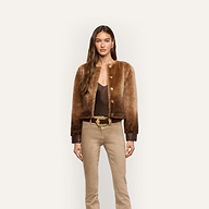 A model wears a brown ombré Voltaire Shearling Jacket over a dark brown camisole and tan trousers with a gold-buckled belt.