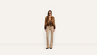 A woman wears a brown fur jacket over a dark top, paired with tan flared pants, a gold-toned belt, and sunglasses.