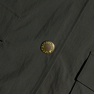 Close-up of the Axel Windbreaker Trench, a dark fabric utility jacket featuring large, round gold buttons engraved with “Burberry London England” and two rectangular front pockets.