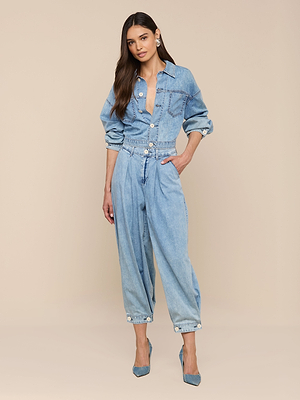 A woman poses in the Gaines Jean Jacket, a light blue featherweight denim piece with rolled-up sleeves, paired with blue pointed heels and set against a plain beige background.