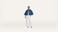 Woman stands facing forward, wearing a blue denim jacket over a white top and white wide-leg pants, with white heeled sandals, on a plain white background.