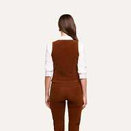 Wearing the Yelena Vest over a white long-sleeve shirt and matching stretch corduroy pants, a woman stands with her straight brown hair falling down her back against a plain light background.