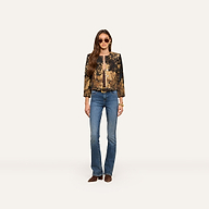 A woman stands facing forward against a plain light background, wearing sunglasses, blue jeans, brown shoes, and the Lian Tapestry Jacket, her hands by her sides.