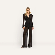 A woman wears a black sheer long-sleeved Rouvier Blazer Top with statement shoulders and matching tailored wide-leg trousers.