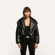 A person wearing a black cropped Vail Puffer with an oversized collar, a black top, and black jeans.