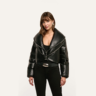 A person wearing a black cropped Vail Puffer jacket with an oversized collar over a black top and jeans.