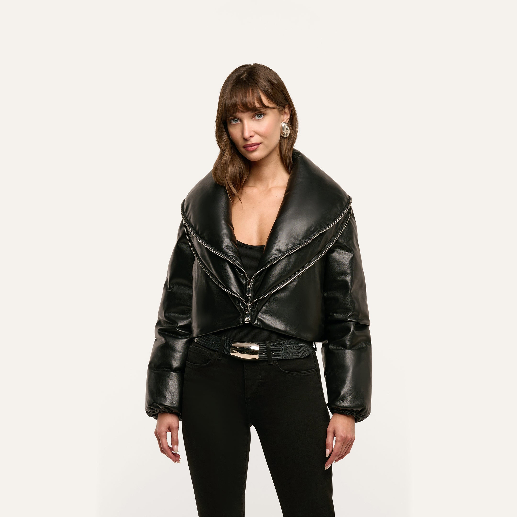 A person wearing a black cropped Vail Puffer jacket with an oversized collar over a black top and jeans.
