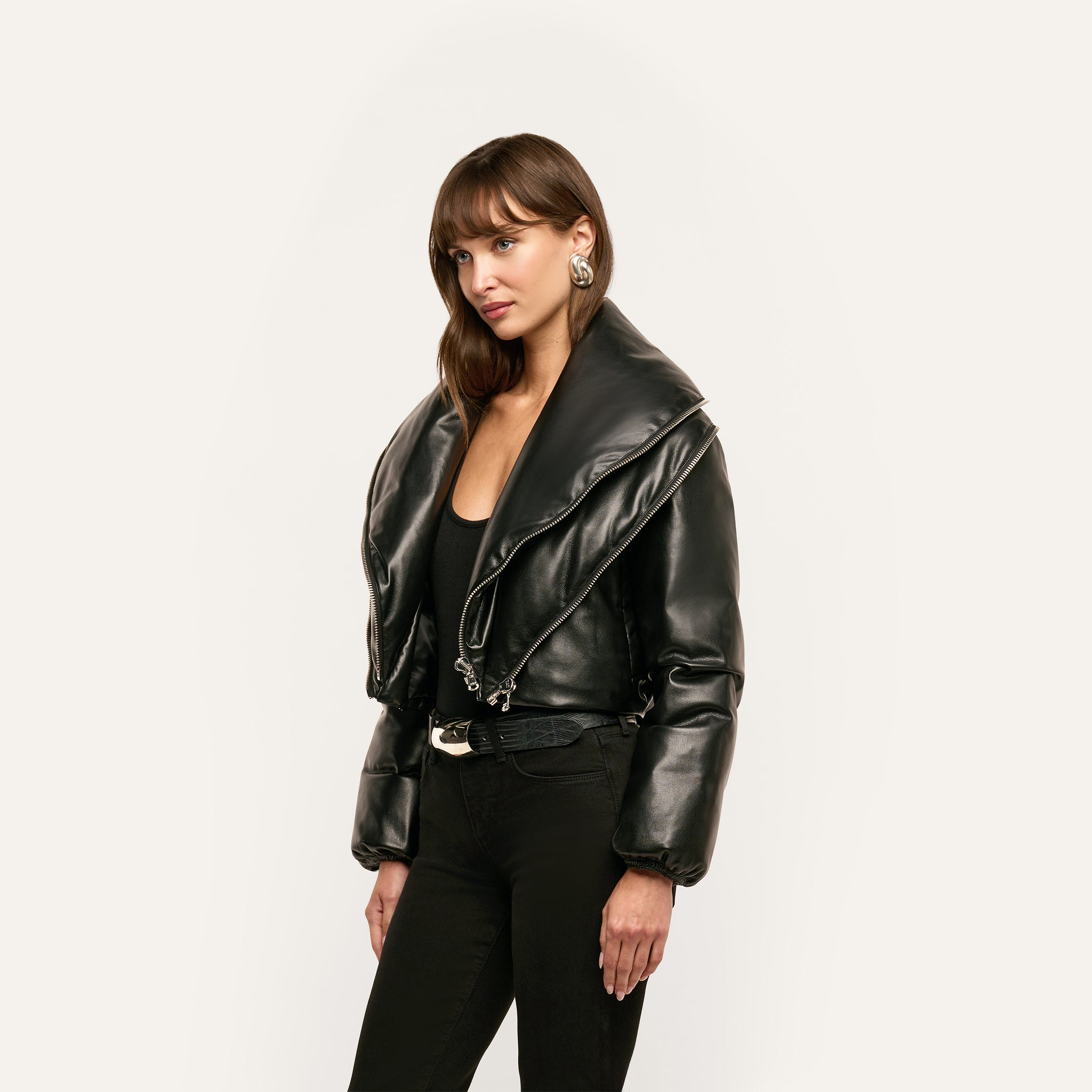 A woman wearing a black cropped Vail Puffer with an oversized collar over a black top and pants.