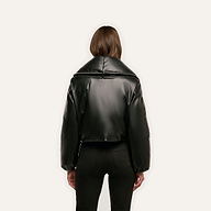 Back view of a person wearing a black cropped Vail Puffer jacket with a wide, zipped-up collar.