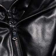 Close-up of a black faux leather Vail Puffer jacket featuring a silver metal zipper.
