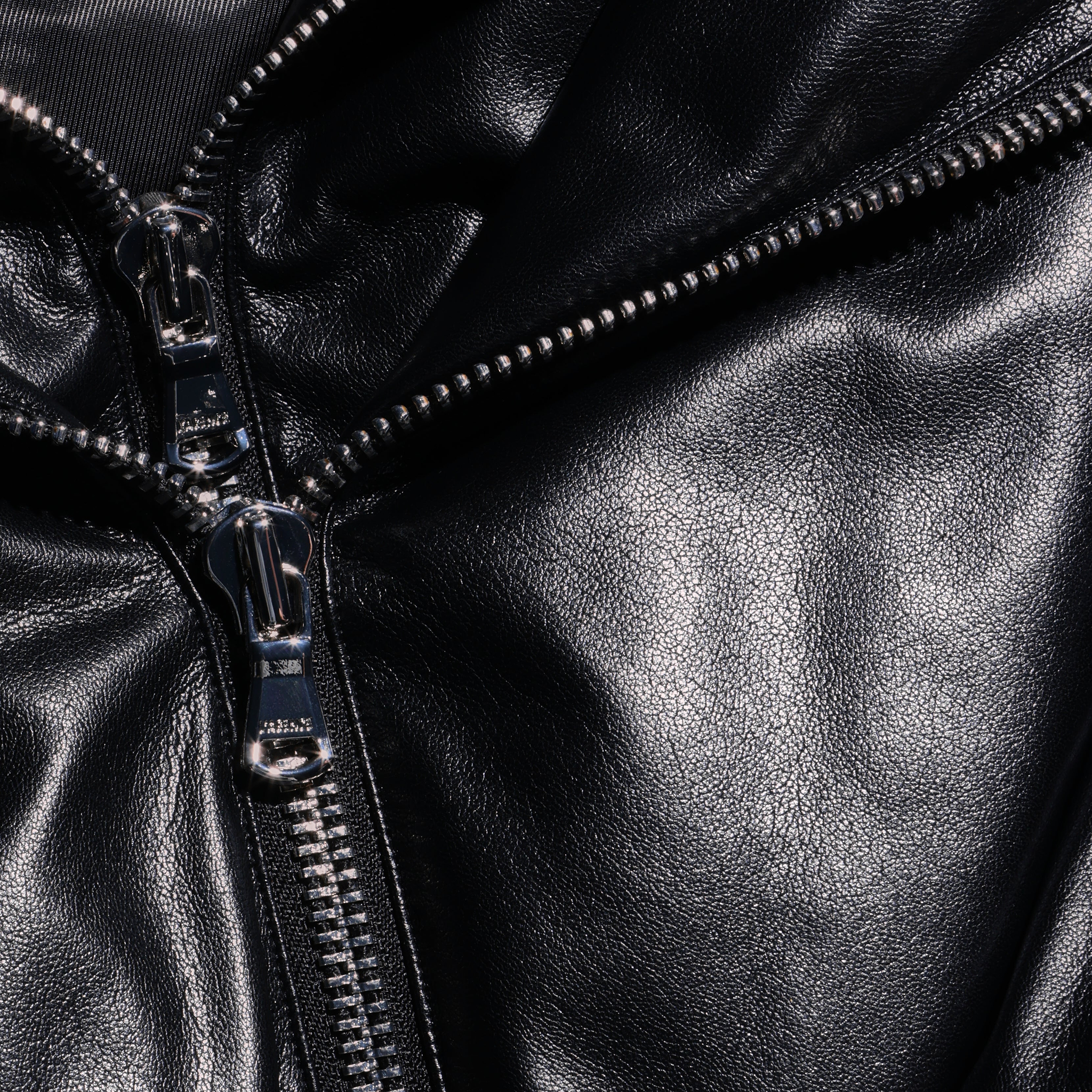 Close-up of a black faux leather Vail Puffer jacket featuring a silver metal zipper.