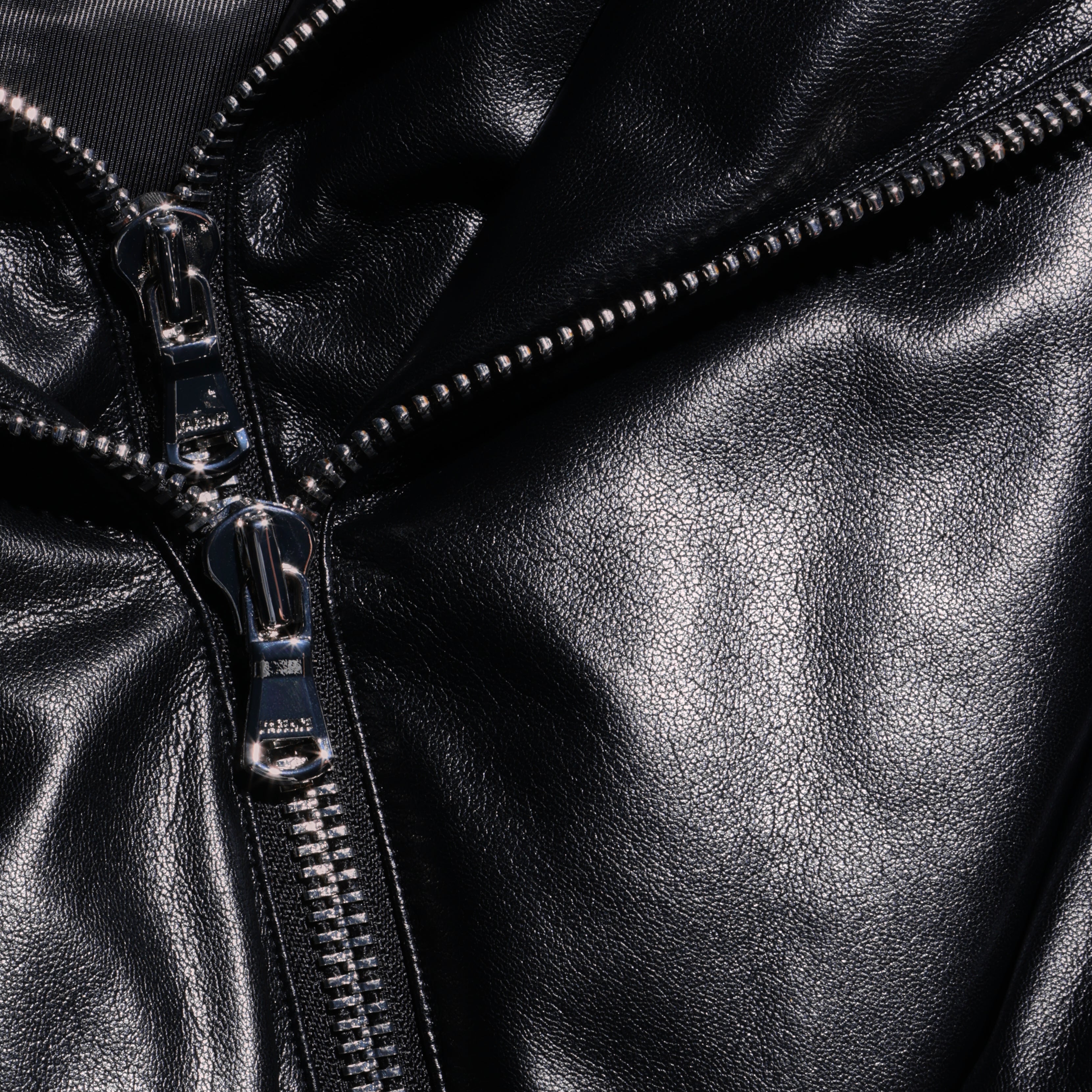 Close-up of a black faux leather Vail Puffer jacket featuring a silver metal zipper.