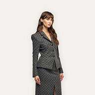 A woman wearing a charcoal-grey, velvet flocked polka-dot Odile Blazer and matching knee-length skirt with a front slit.