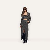 A woman wearing an Odile Blazer in fitted, velvet flocked polka-dot, with a matching lace-trimmed crop top and a long skirt with a front slit.