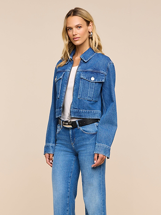 Woman wearing the Micah Oversized Jean Jacket in blue over a white shirt and blue jeans, standing against a plain beige background.