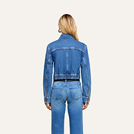 A person with long blonde hair, wearing the Micah Oversized Jean Jacket in an indigo wash and blue oversized jeans, is standing facing away from the camera against a plain white background.