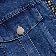 Close-up of the Micah Oversized Jean Jacket in indigo wash, featuring a metal button engraved with LAGENCE and a brass zipper on the right side, highlighting the pocket and detailed stitching.