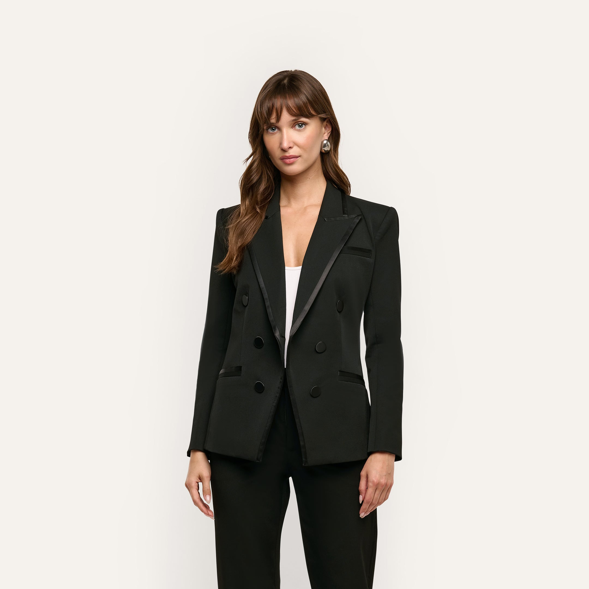 A woman wears a Kyomi Double-Breasted Blazer with satin-finish lapels over a white top.