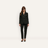 A model wearing a black, tailored Kyomi Double-Breasted Blazer, matching trousers, and high heels against a plain background.
