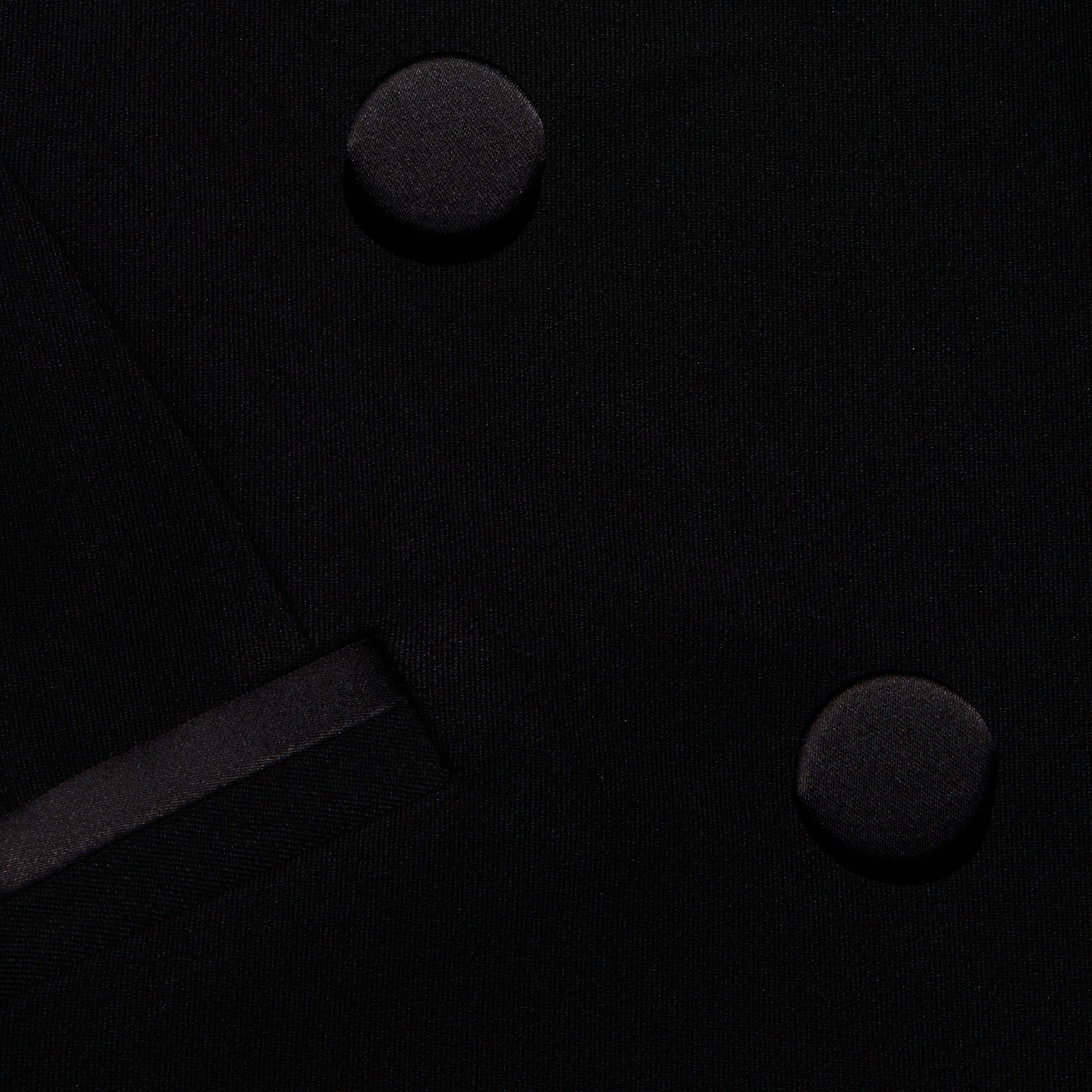 Close-up of the black Kyomi Double-Breasted Blazer showing two fabric-covered buttons and a satin-trimmed lapel in tailored stretch suit fabric.