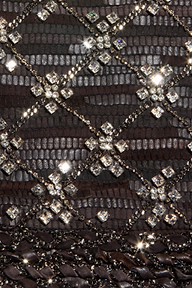 Close-up of a dark textured surface with a diamond pattern formed by sparkling square and round crystals connected by thin, shiny lines, echoing the crystal chain details featured on the Morrisa Embellished Leather Jacket.