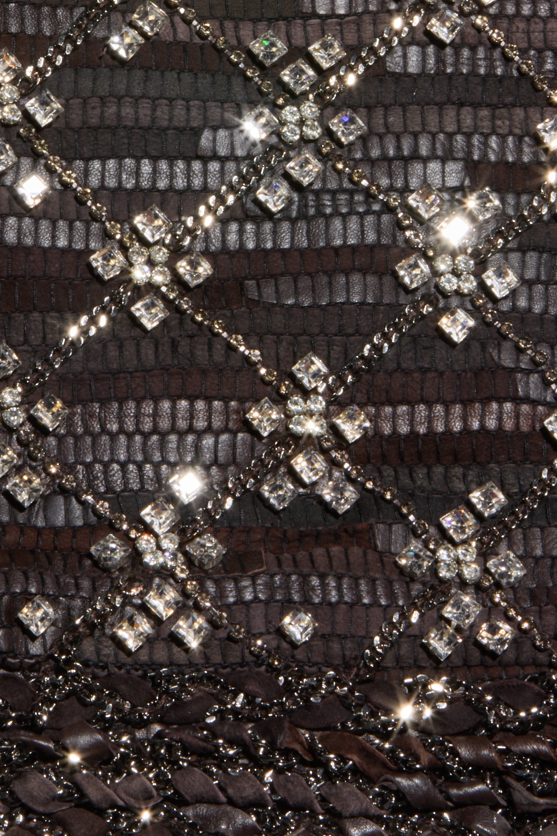 Close-up of a dark textured surface with a diamond pattern formed by sparkling square and round crystals connected by thin, shiny lines, echoing the crystal chain details featured on the Morrisa Embellished Leather Jacket.