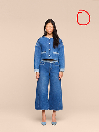 A woman stands facing forward, wearing the Arabell Romper with pointed-toe heels—her look capturing the effortless versatility of a warm weather essential—against a plain beige background.