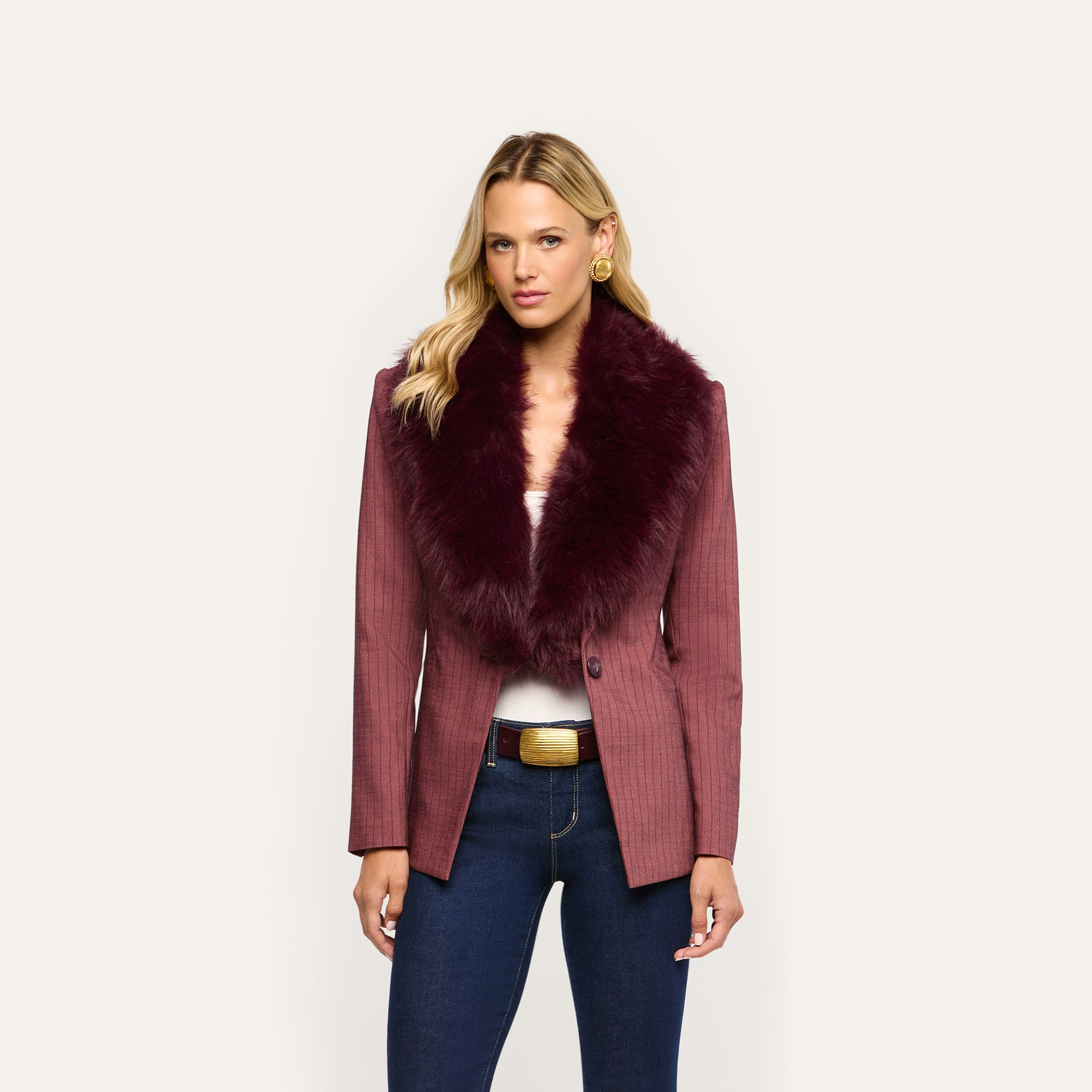 The Sheila Blazer, a maroon pinstriped jacket with a large faux fur collar, worn with dark blue jeans and a gold-buckled belt.