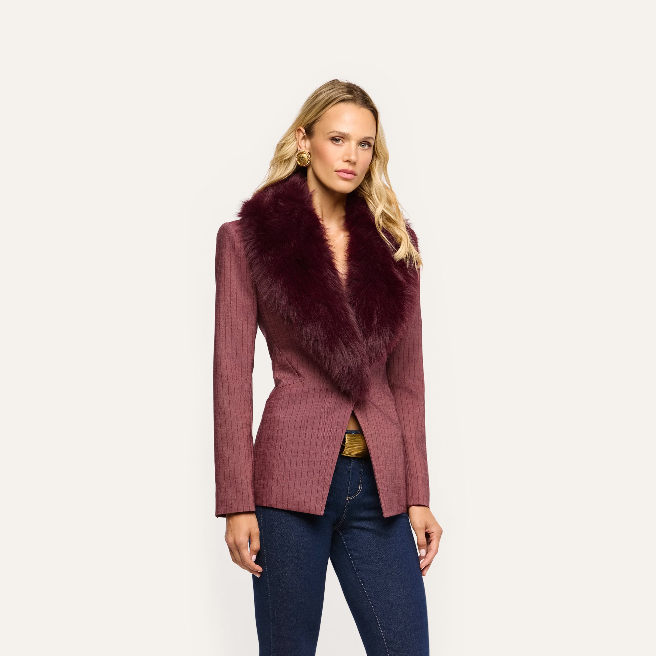 A model wears a mauve pinstripe Sheila Blazer with a deep burgundy faux fur collar over blue jeans.