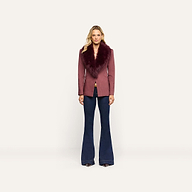 A woman wearing a mauve pinstripe Sheila Blazer with a wide faux-fur collar and dark denim flared jeans.