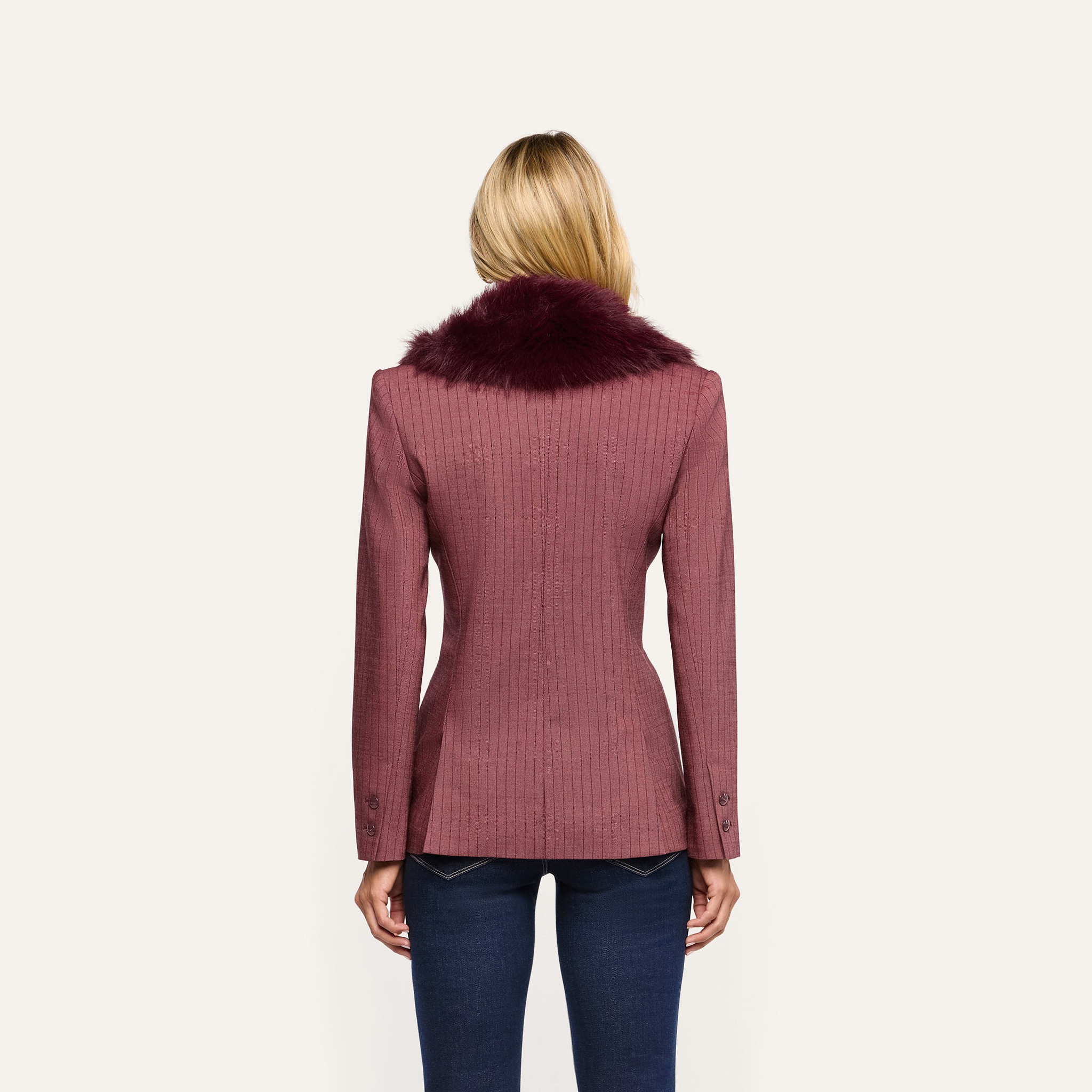 Back view of a person wearing a Sheila Blazer in mauve pinstriped fabric with a dark burgundy faux fur collar and blue jeans.