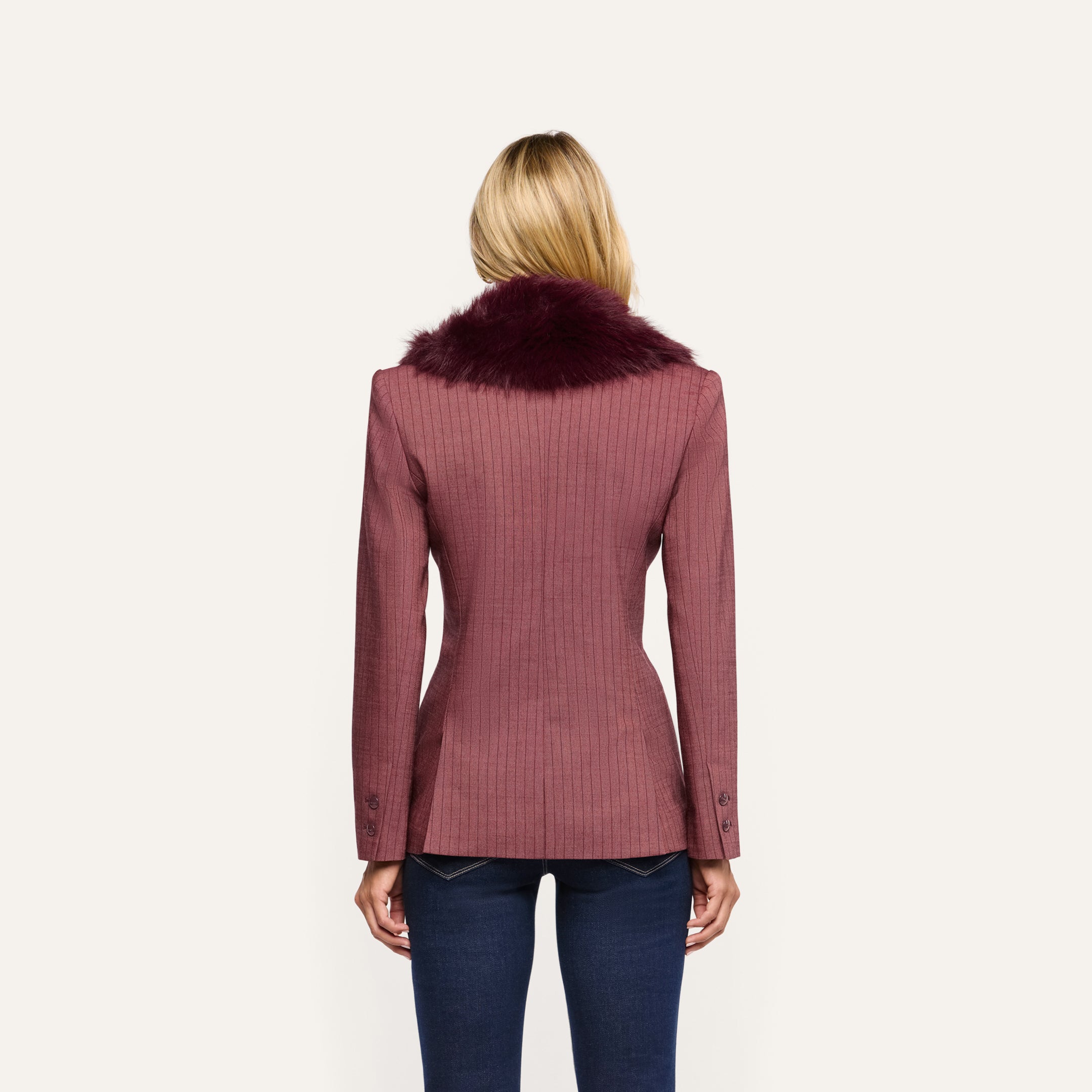 Back view of a person wearing a Sheila Blazer in mauve pinstriped fabric with a dark burgundy faux fur collar and blue jeans.