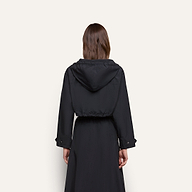 Back view of a person wearing a water-repellant, black hooded Derby Windbreaker with a cropped silhouette.