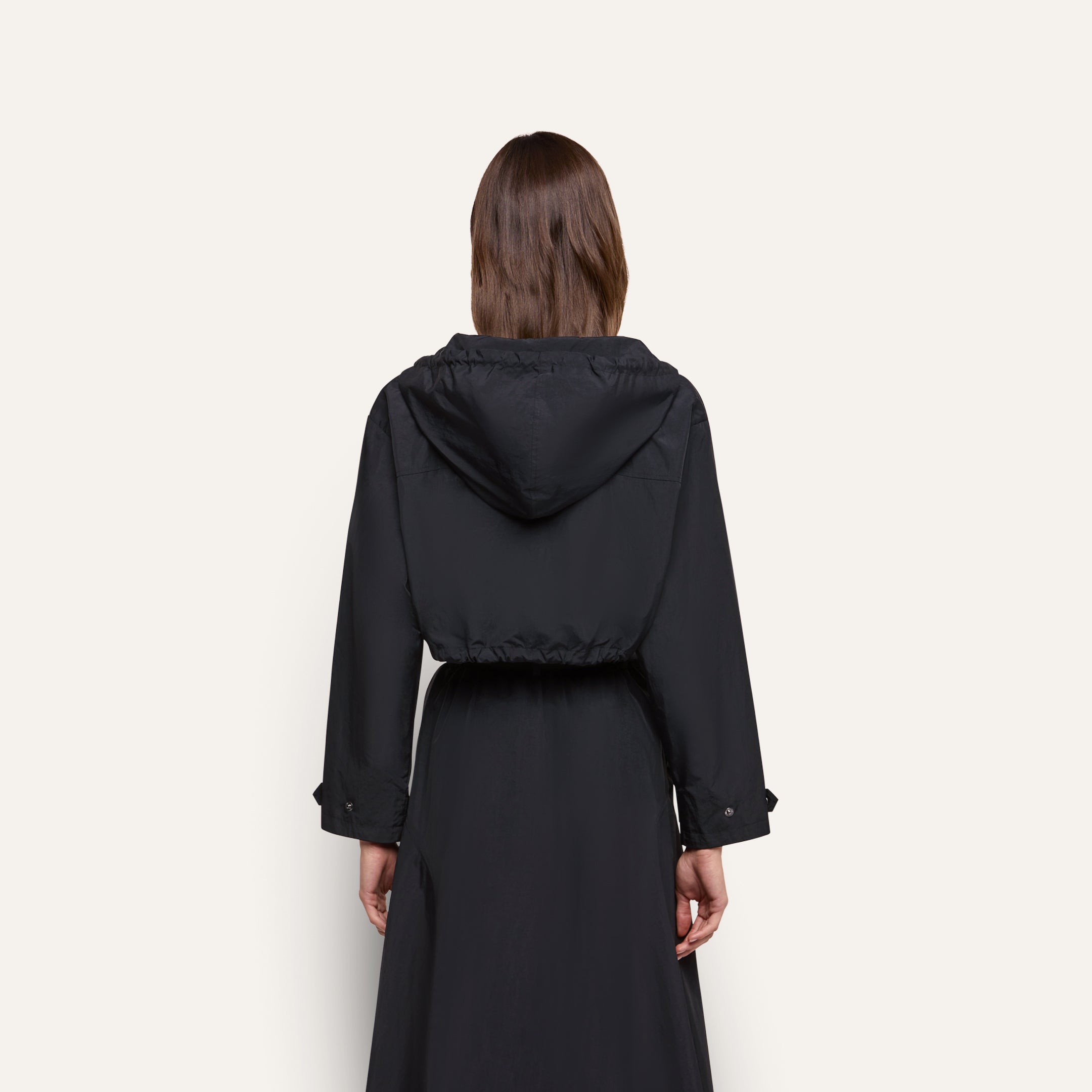 Back view of a person wearing a water-repellant, black hooded Derby Windbreaker with a cropped silhouette.