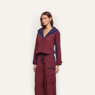 A person wearing a maroon and dark blue Geovana Windbreaker with matching cargo pants.