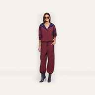 A person wearing a maroon Geovana windbreaker with blue collar trim and matching maroon cargo-style joggers with a drawstring waist.